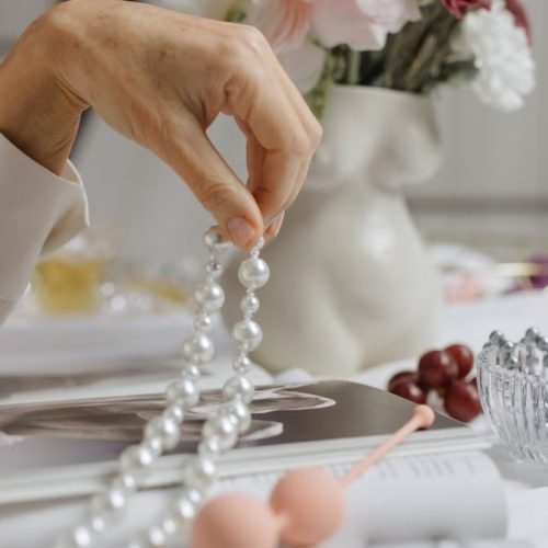 A sophisticated arrangement of pearls, flowers, and a magazine depicting elegance and grace.