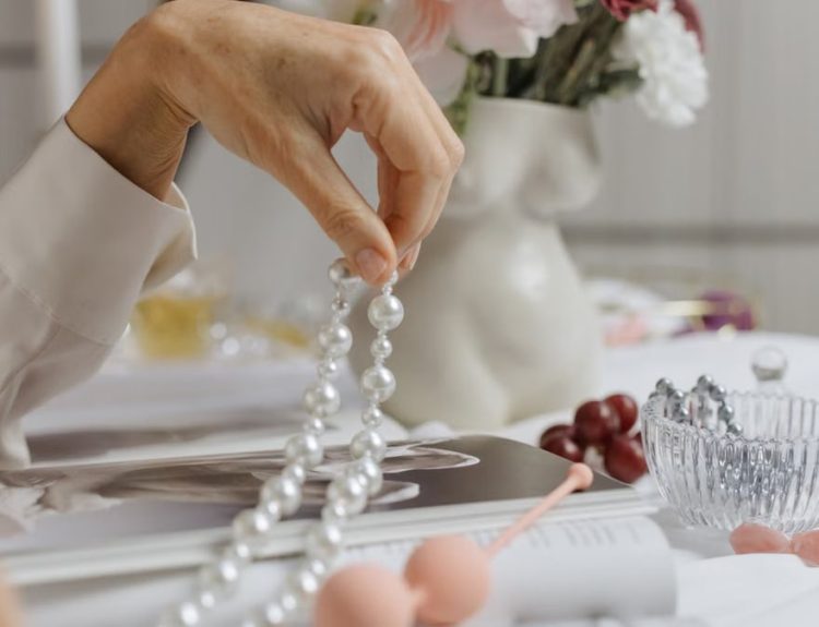 A sophisticated arrangement of pearls, flowers, and a magazine depicting elegance and grace.
